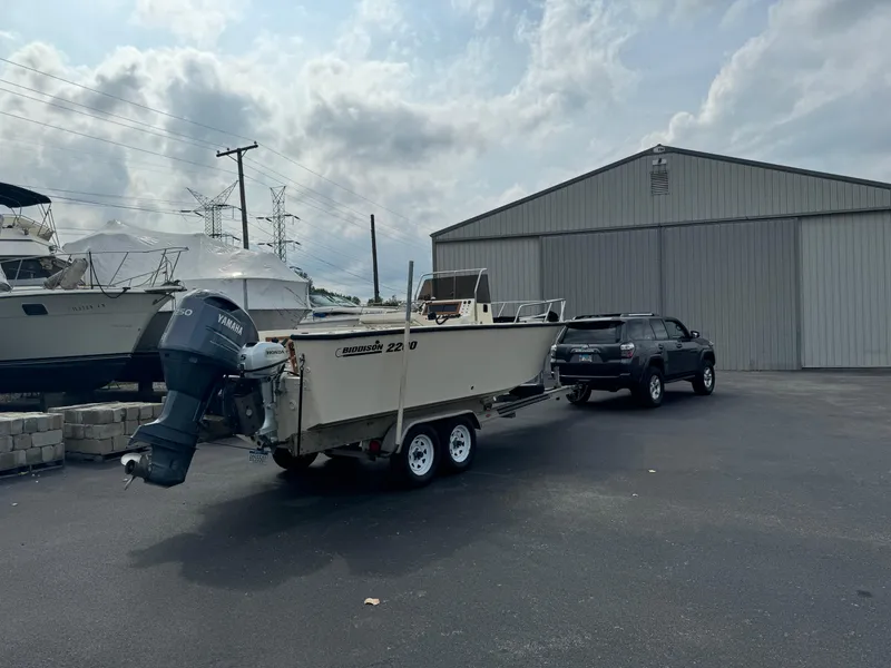 Slide: The Image of 1987 Custom Biddison 2200 boat on trailer, parked near a large metal building. - 17