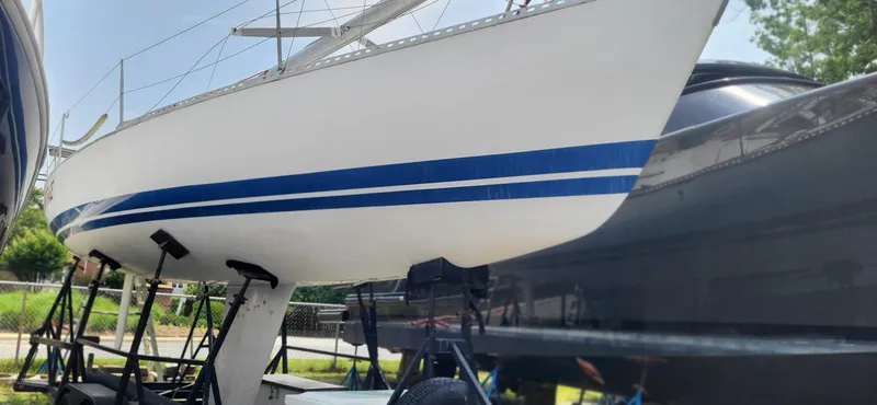 Slide: The Image of 1983 Beneteau First Class 10 sailboat with blue stripes on a trailer. - 10