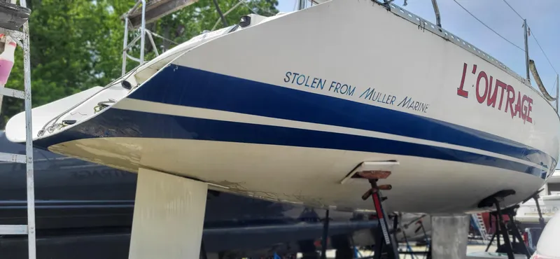 Slide: The Image of 1983 Beneteau First Class 10 sailboat on stands, featuring "L'Outrage" and "Stolen from Muller Marine" text. - 14