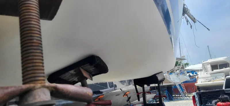 Slide: The Image of 1983 Beneteau First Class 10 sailboat on dry dock, supported by stands, with other boats nearby. - 16