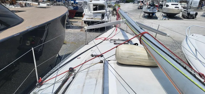 Slide: The Image of Beneteau First Class 10 sailboat, 1983 model, docked with mast down, surrounded by other boats. - 2