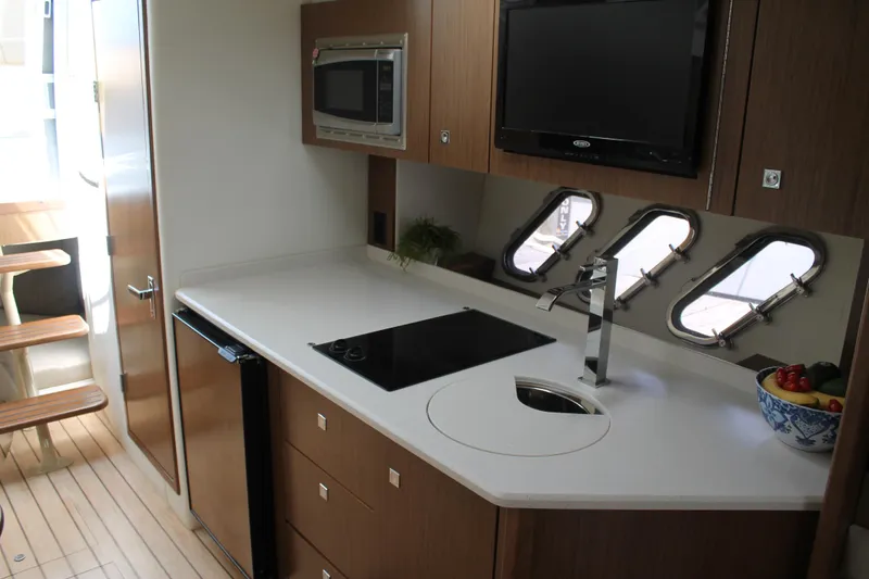 Slide: The Image of 2014 Cruisers Yachts 350 Express kitchen with stove, sink, microwave, and windows. - 39