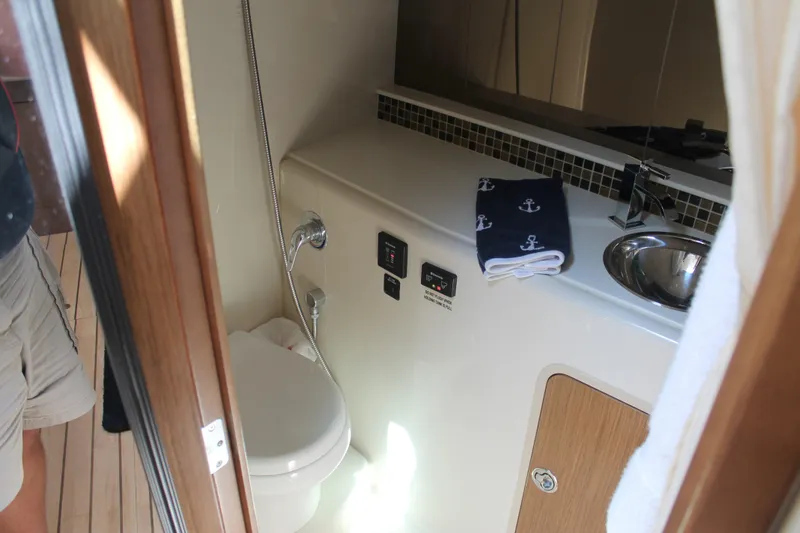 Slide: The Image of 2014 Cruisers Yachts 350 Express bathroom with sink, toilet, and nautical-themed towel. - 45