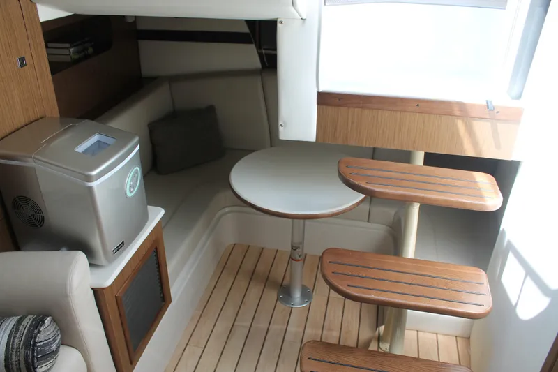 Slide: The Image of 2014 Cruisers Yachts 350 Express interior with wooden steps, seating, and compact table. - 47