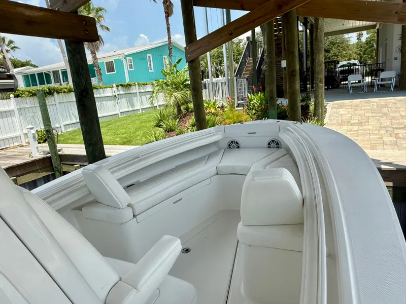 Slide: The Image of 2023 Regulator 23 boat with white seating, docked near a landscaped yard. - 12