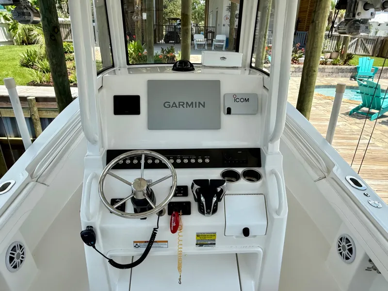 Slide: The Image of 2023 Regulator 23 boat console with Garmin and Icom electronics, steering wheel, and cup holders. - 15