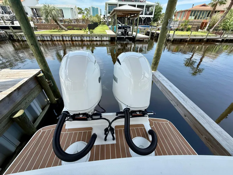 Slide: The Image of 2023 Regulator 23 boat with dual outboard motors docked in a serene canal setting. - 19