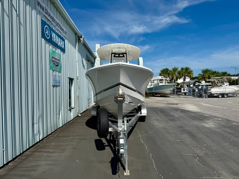 Slide: The Image of 2023 Regulator 23 boat on trailer outside dealership, clear sky, palm trees in background. - 3