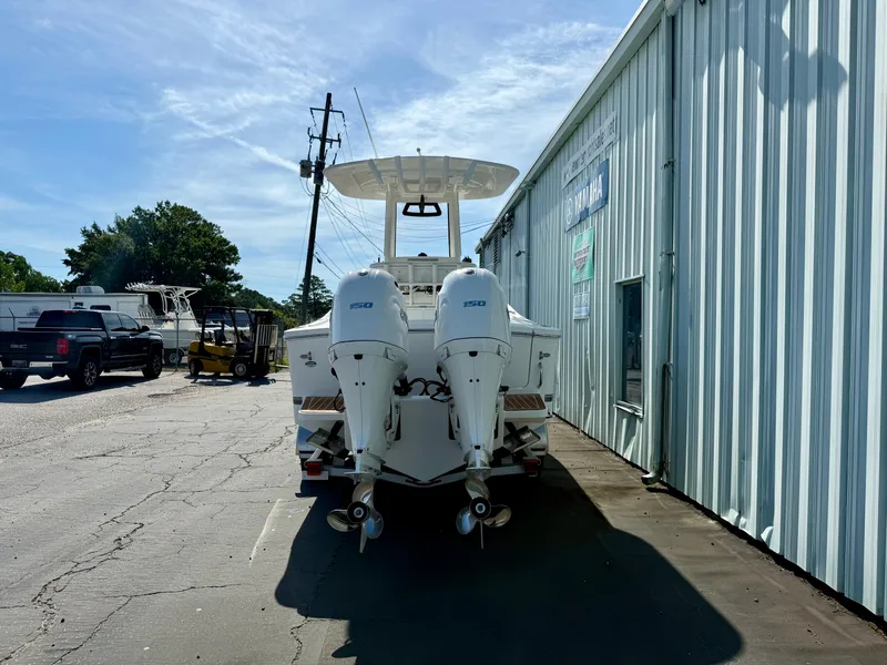 Slide: The Image of 2023 Regulator 23 boat with dual outboard engines parked outside a metal building. - 4