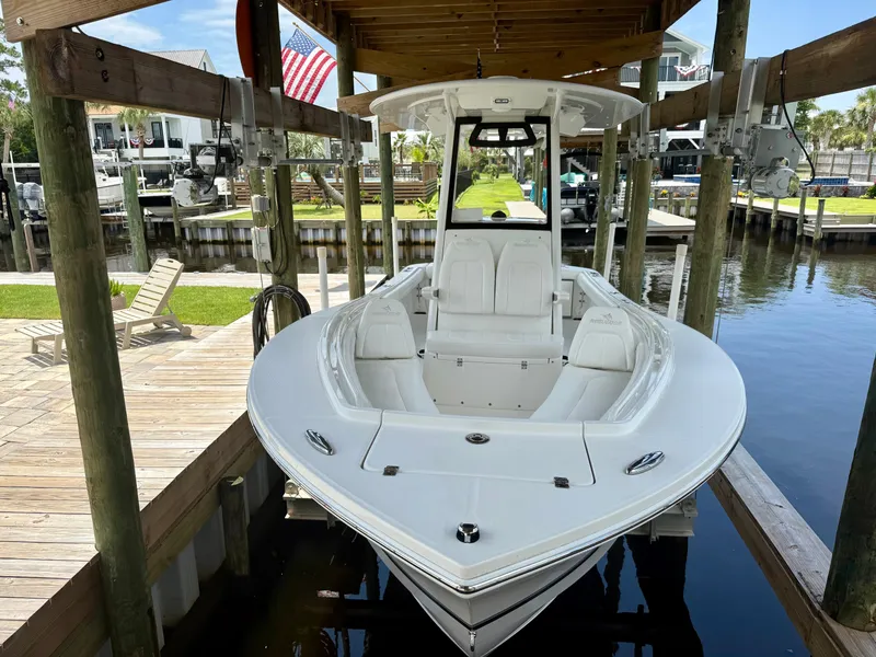 Slide: The Image of 2023 Regulator 23 boat docked under a wooden shelter by the water. - 7