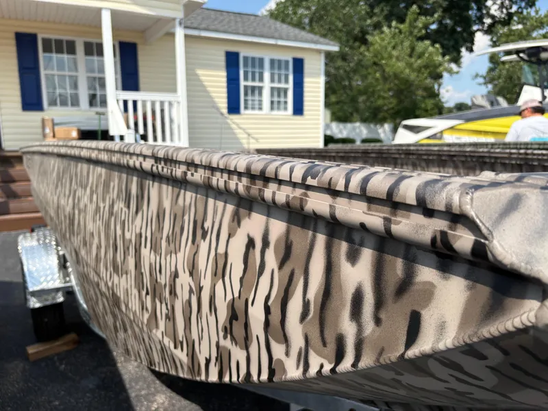 Slide: The Image of 2025 Edge Duck Boats Standard 656DB with camouflage design, parked near a house. - 1