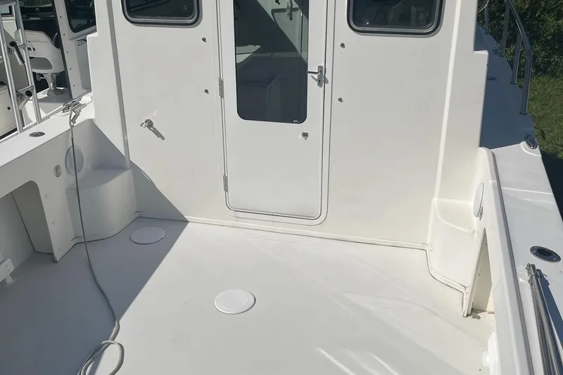 Slide: The Image of 2020 Parker 2530 Extended Sport Cabin boat deck with white exterior and cabin door. - 12