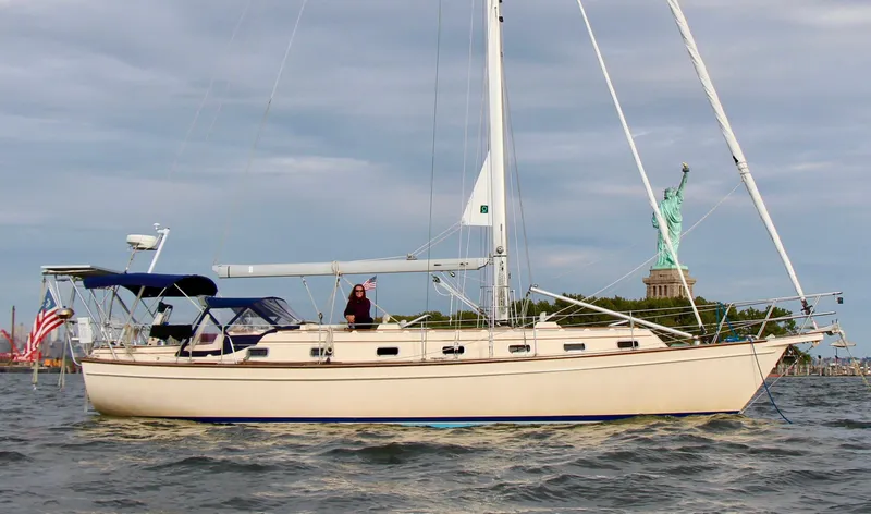 Slide: The Image of 1999 Island Packet 45 sailboat near Statue of Liberty, clear sky, calm waters. - 0