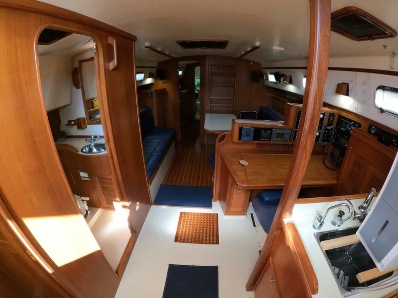 Slide: The Image of Interior of a 1999 Island Packet 45 sailboat, featuring wood finishes and a compact kitchen area. - 10