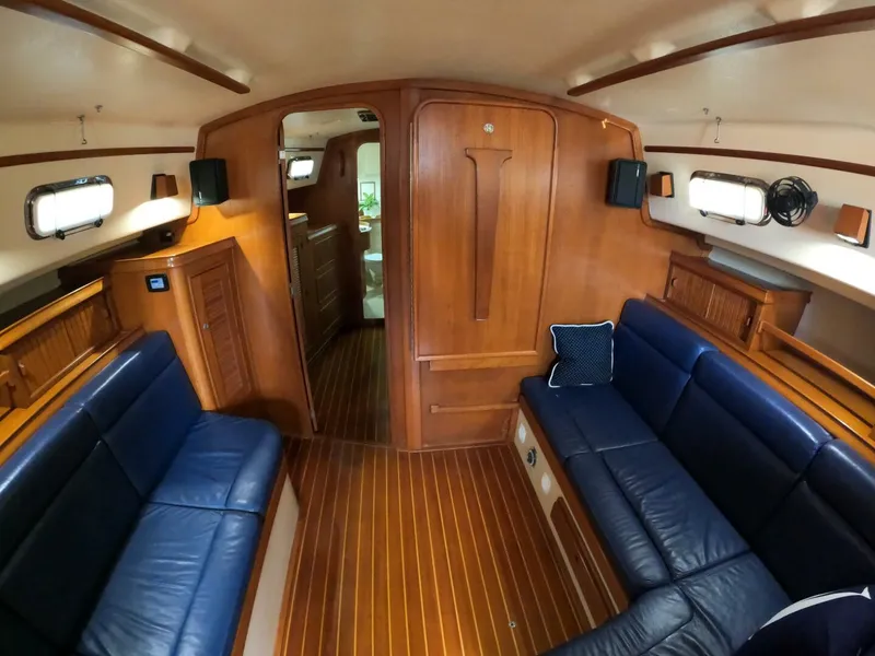 Slide: The Image of Interior of 1999 Island Packet 45 yacht with blue leather seating and wooden finishes. - 11