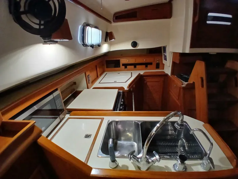 Slide: The Image of Interior of 1999 Island Packet 45 yacht, featuring a well-equipped kitchen with sink and stove. - 15
