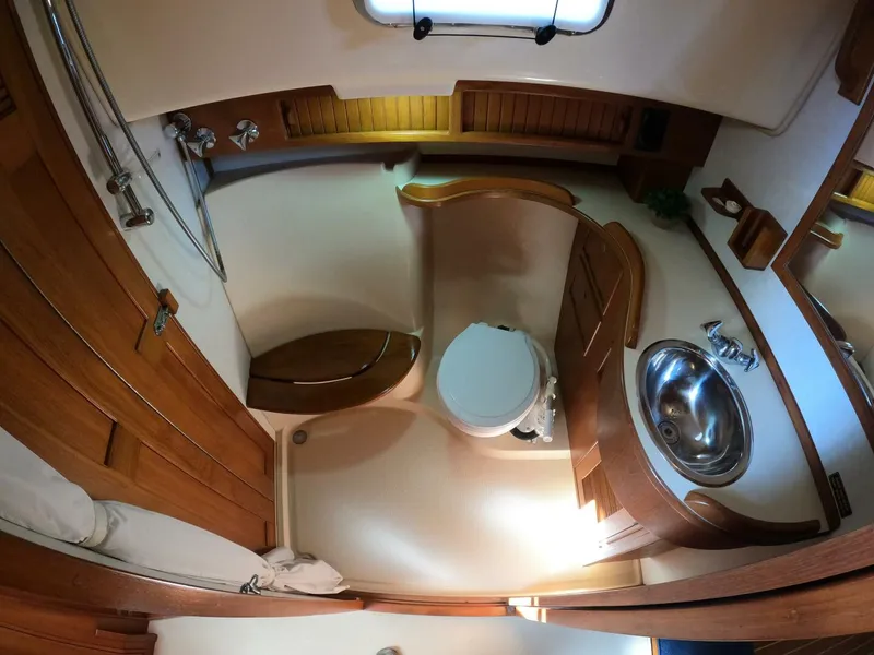 Slide: The Image of 1999 Island Packet 45 yacht bathroom with wooden cabinetry, toilet, and stainless steel sink. - 29
