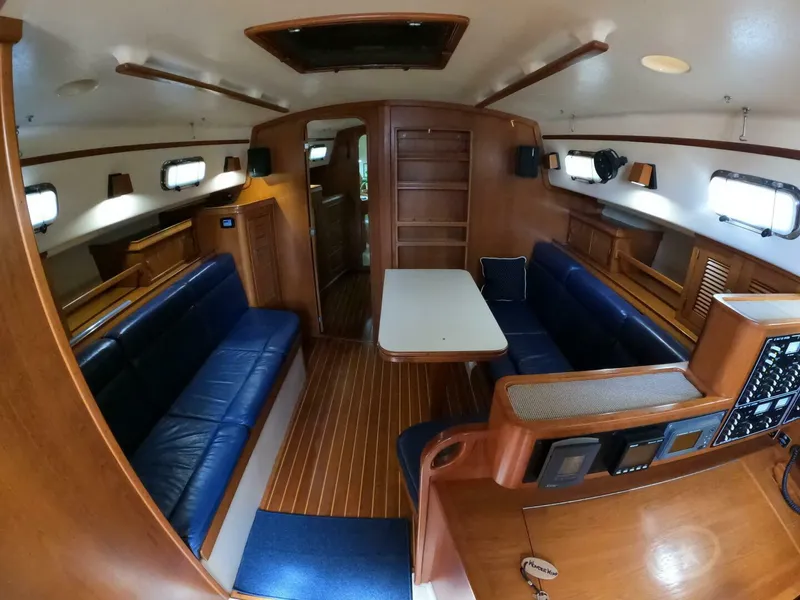 Slide: The Image of Interior of 1999 Island Packet 45 sailboat with blue seating and wooden finishes. - 3
