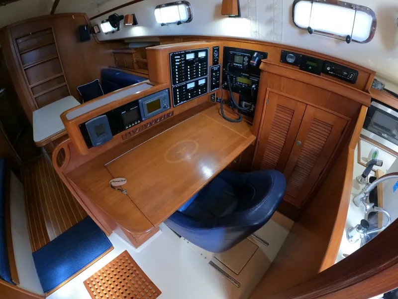 Slide: The Image of Navigation station inside 1999 Island Packet 45 yacht, featuring control panels and seating. - 33