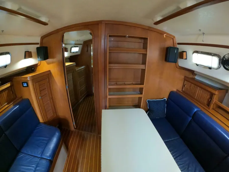 Slide: The Image of Interior of 1999 Island Packet 45 sailboat with blue seating and wooden cabinetry. - 8