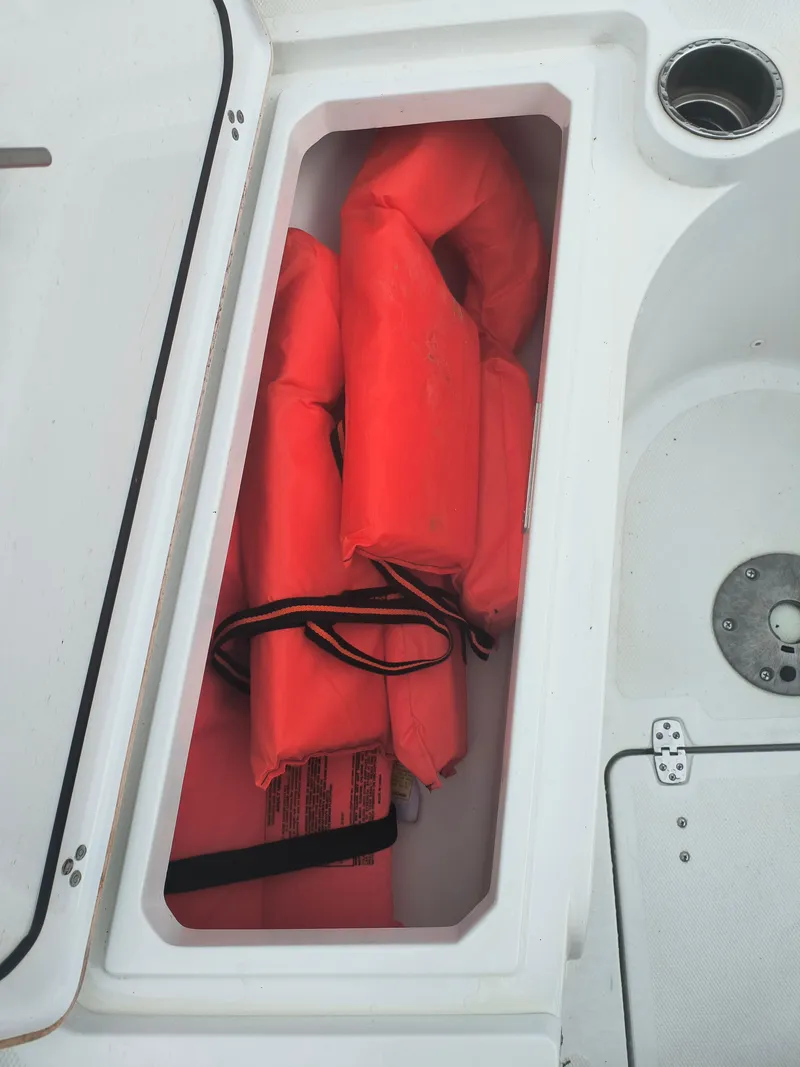 Slide: The Image of Storage compartment with orange life jackets on a 2020 Wellcraft 222 Fisherman boat. - 18