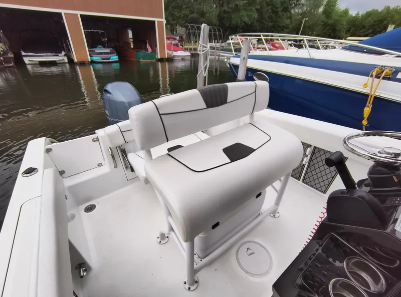 Slide: The Image of 2020 Wellcraft 222 Fisherman boat interior with seating and steering wheel at a marina. - 21