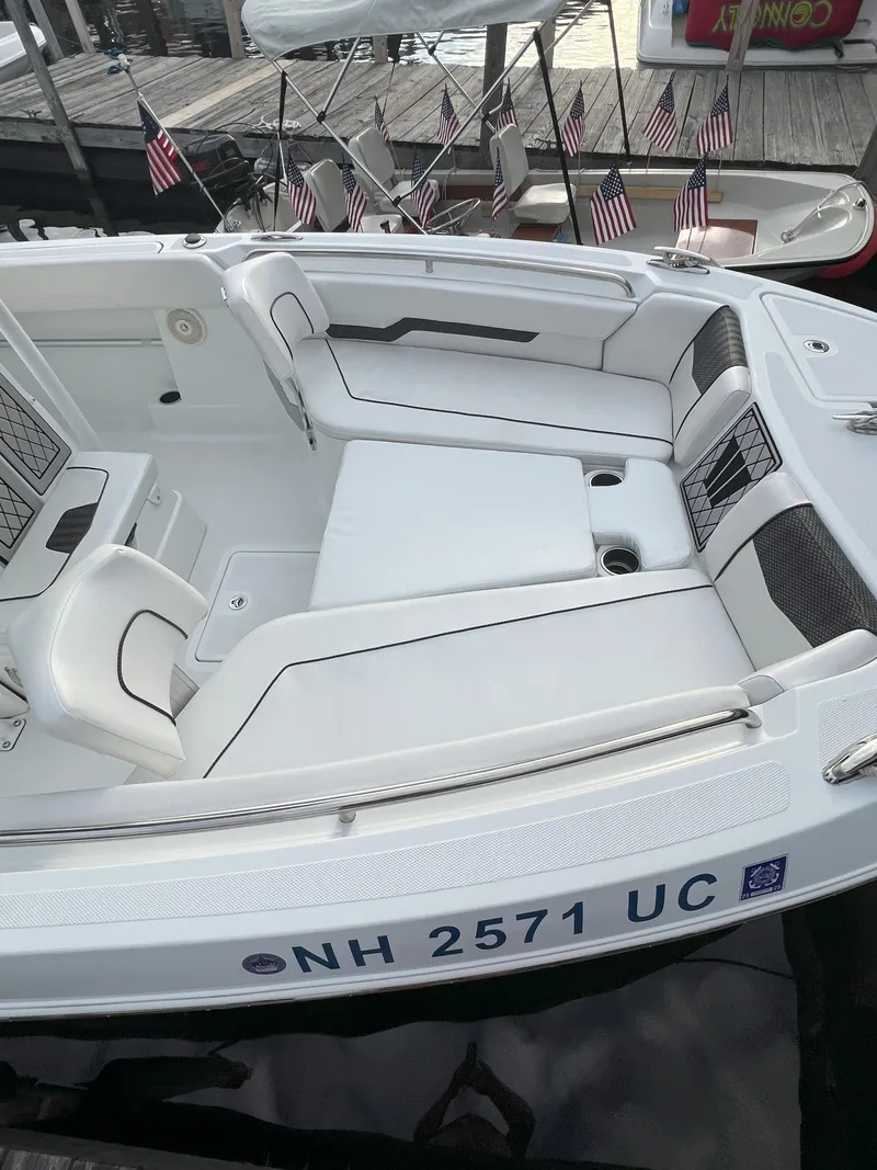 Slide: The Image of 2020 Wellcraft 222 Fisherman boat interior with white seating, docked near American flags. - 7