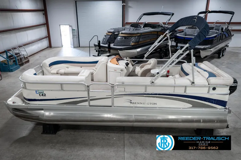 Slide: The Image of 2007 Bennington 2050 GL pontoon boat in showroom, featuring white and blue design. - 1