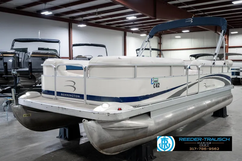 Slide: The Image of 2007 Bennington 2050 GL pontoon boat in indoor showroom, featuring sleek design and blue accents. - 2