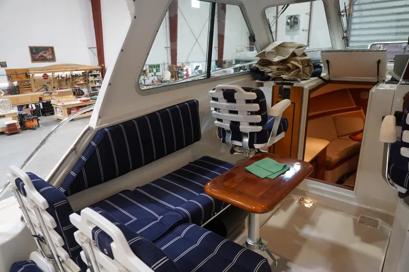 Slide: The Image of 2006 Back Cove 29 boat interior with striped seating and wooden table in a workshop setting. - 12
