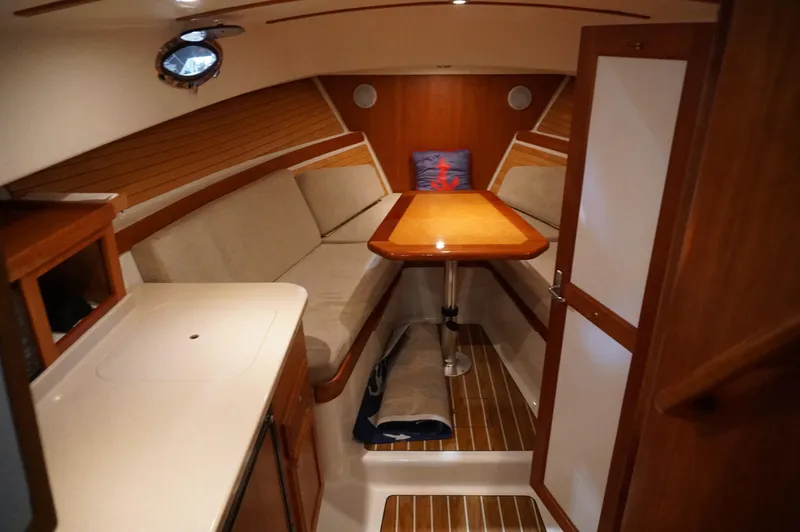 Slide: The Image of 2006 Back Cove 29 boat interior with cozy seating, wooden table, and compact kitchenette. - 13