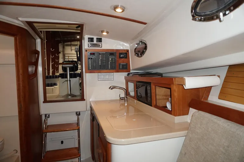 Slide: The Image of 2006 Back Cove 29 yacht interior with kitchenette, control panel, and wooden cabinetry. - 16