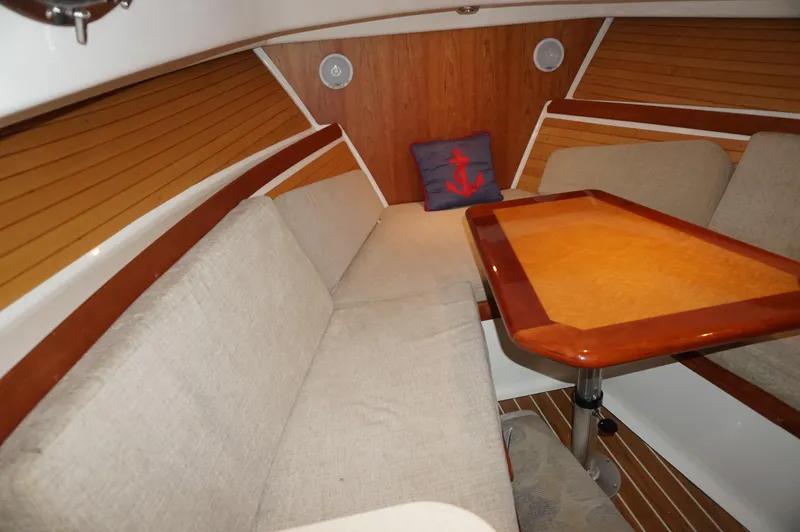 Slide: The Image of 2006 Back Cove 29 interior with wooden table, beige seating, and nautical-themed pillow. - 22