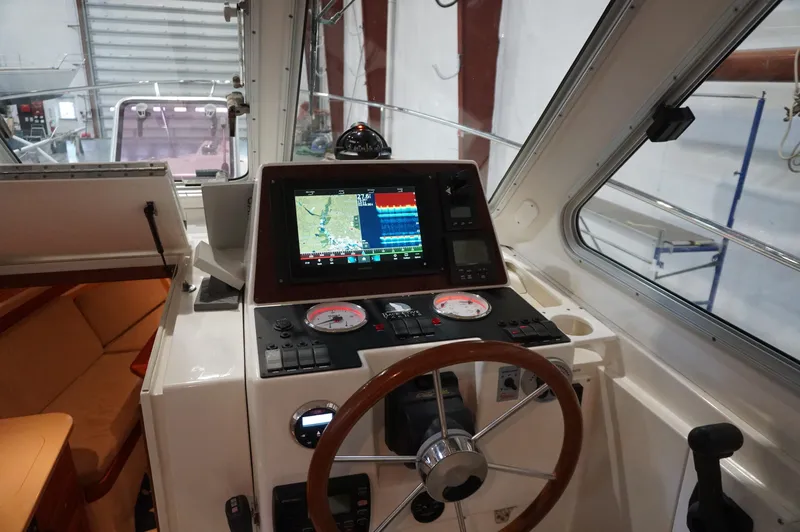 Slide: The Image of 2006 Back Cove 29 boat helm with navigation display and steering wheel in a cabin setting. - 23