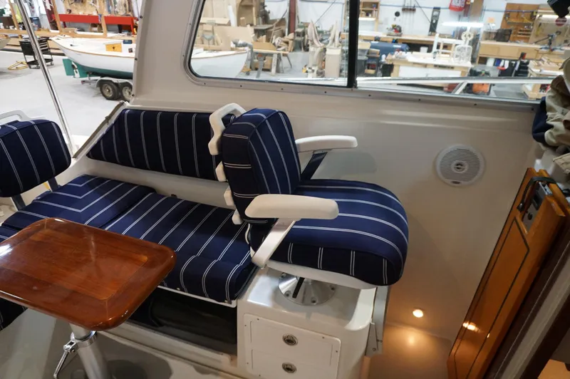 Slide: The Image of Interior of 2006 Back Cove 29 boat with striped seating and wooden table. - 26