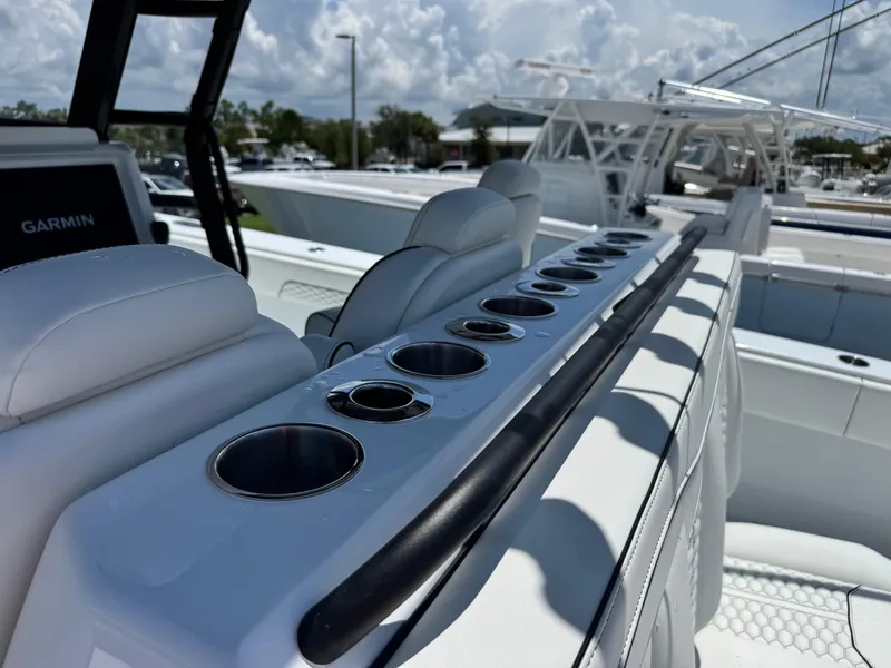 Slide: The Image of 2026 Invincible 38 Catamaran interior with cup holders and seating, under a cloudy sky. - 16