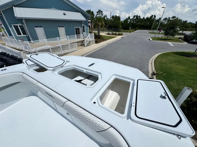 Slide: The Image of 2026 Invincible 38 Catamaran with open storage compartments, docked near a blue building. - 27