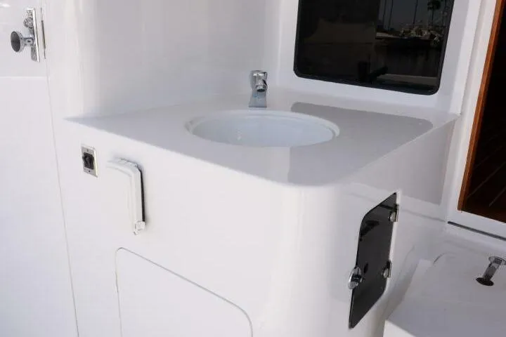 Slide: The Image of White sink area on 2001 Mikelson 61 Yachtfisher, featuring modern fixtures and storage. - 117