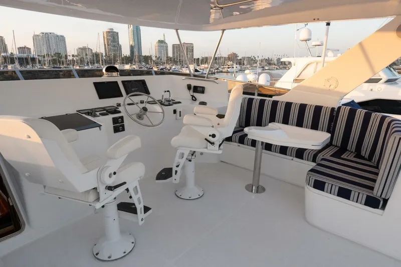 Slide: The Image of 2001 Mikelson 61 Yachtfisher helm with seating, steering wheel, and city skyline view. - 64