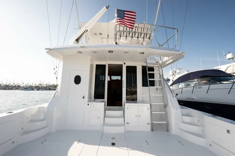 Slide: The Image of 2001 Mikelson 61 Yachtfisher with American flag, docked in marina under clear sky. - 65