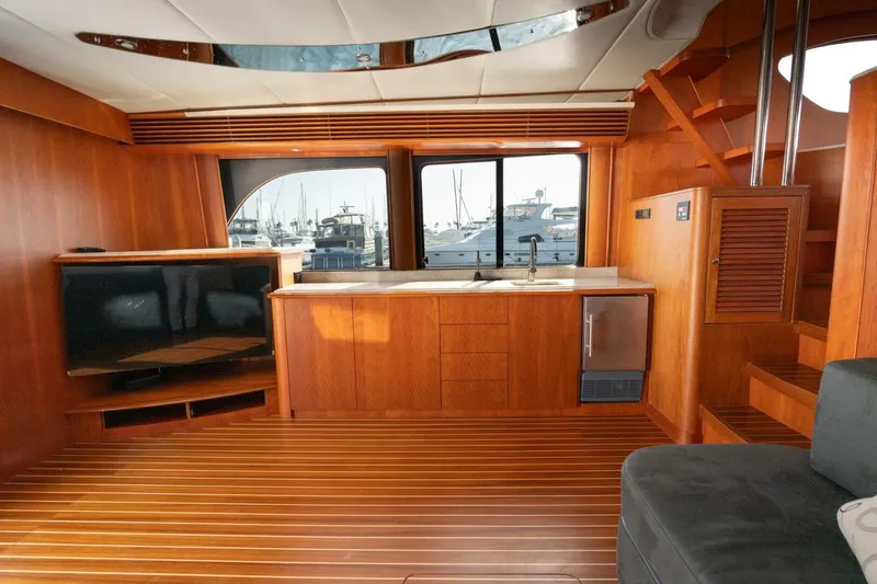 Slide: The Image of Luxurious 2001 Mikelson 61 Yachtfisher interior with wood finish, kitchenette, and marina view. - 70