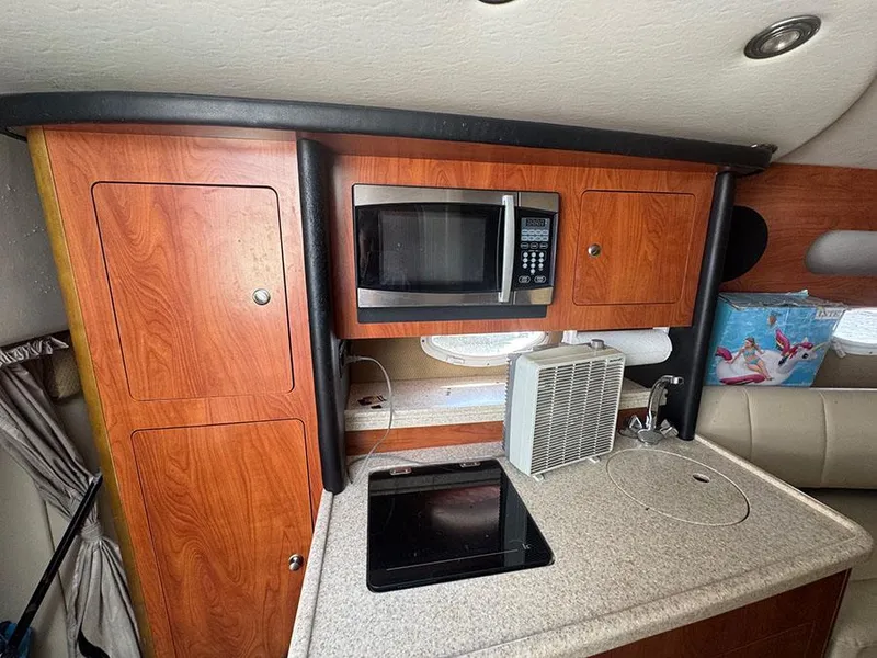 Slide: The Image of 2008 Rinker 280 Express Cruiser interior kitchen with microwave, cabinets, and countertop. - 10
