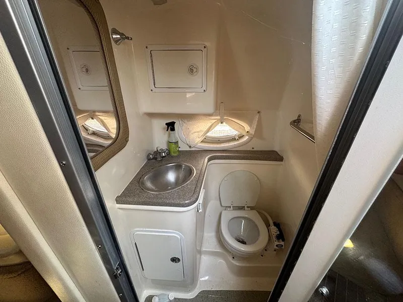 Slide: The Image of 2008 Rinker 280 Express Cruiser bathroom with sink, toilet, and storage cabinets. - 14