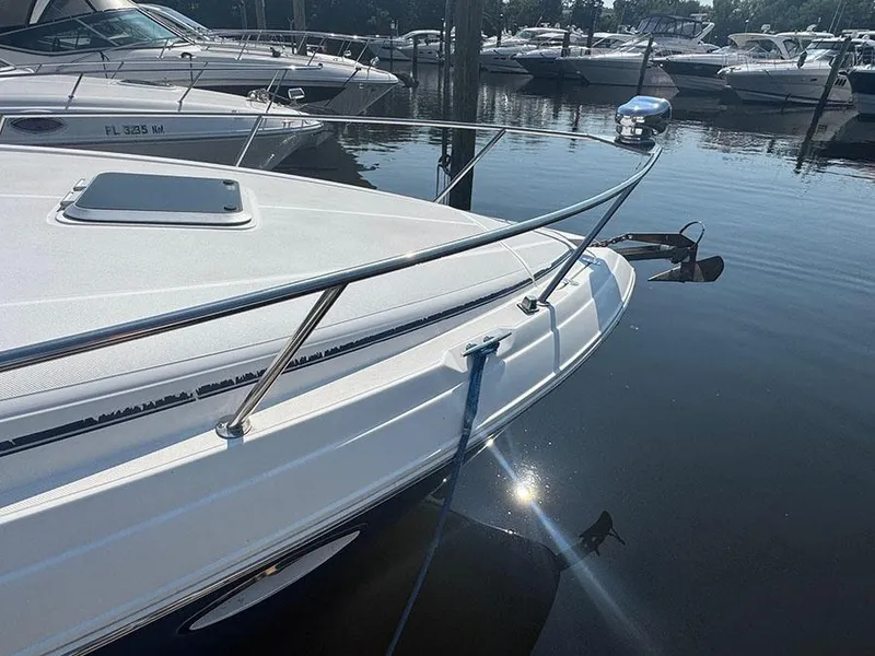 Slide: The Image of 2008 Rinker 280 Express Cruiser docked in a marina, reflecting sunlight on water. - 4