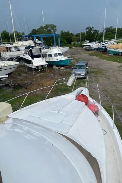 Slide: The Image of 1999 Silverton 392 Motor Yacht in boatyard with other vessels and parked car nearby. - 2