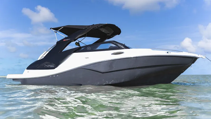 Slide: The Image of 2025 NX Boats NX260 EVOLUTION on water, sleek design, black and white exterior, sunny day. - 3