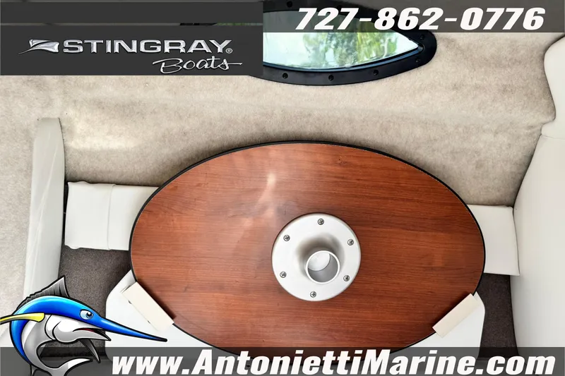 Slide: The Image of 2026 Stingray 212 SC boat interior with wooden table, logo, and contact details. - 34