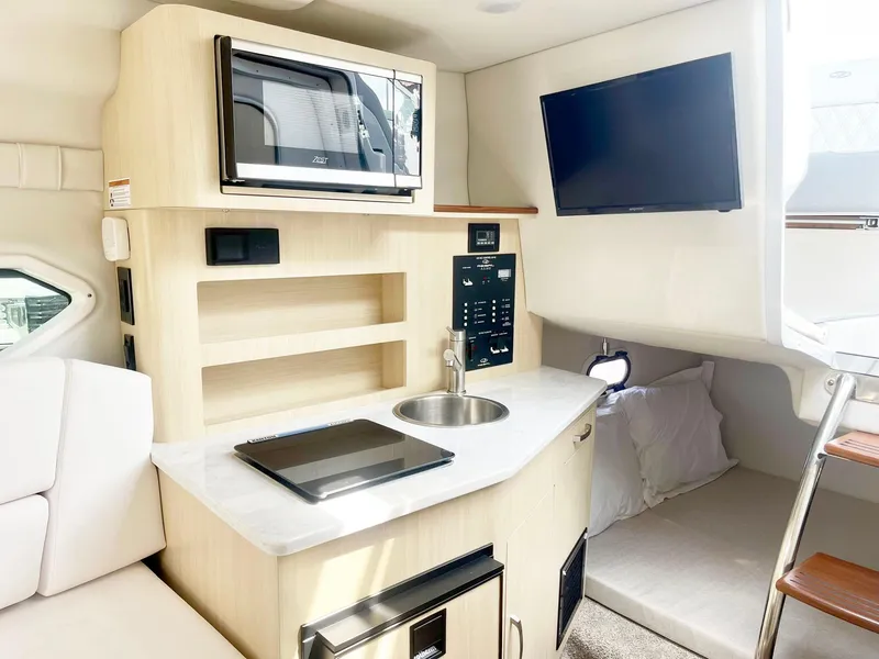 Slide: The Image of 2024 Regal 26XO boat interior with kitchenette, microwave, sink, and TV. - 11