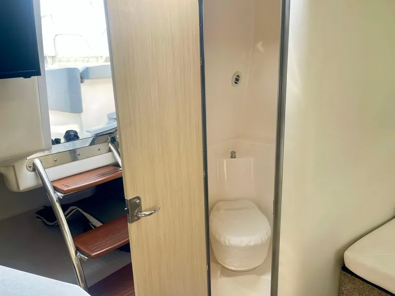 Slide: The Image of 2024 Regal 26XO boat interior with compact bathroom and wooden steps. - 14