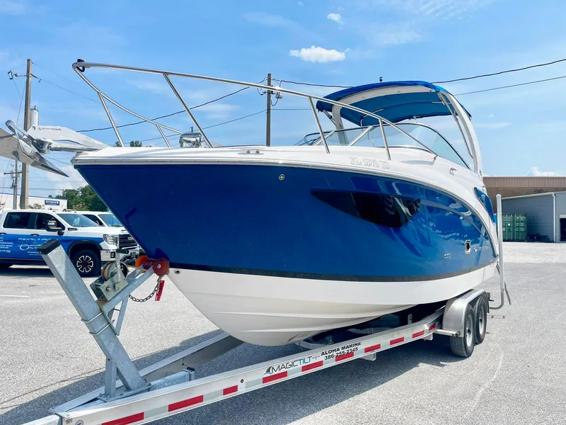 Slide: The Image of 2024 Regal 26XO boat on trailer, blue and white design, parked outdoors. - 2